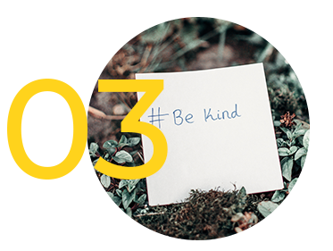Valeur 3 We are ipse, chiffre 03 en jaune sur la gauche et gros plan sur une étiquette blanche dans sur de l'herbe avec un texte "# Be Kind" à droite 
