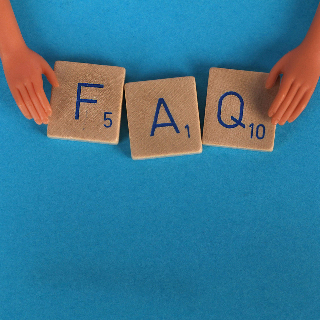 pièce de scrabble en bois qui forme le mot FAQ sur fond bleu